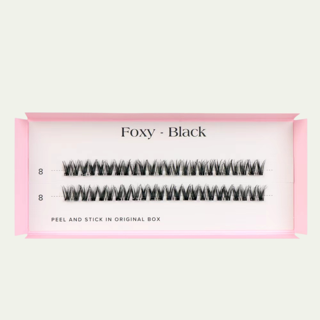 Faux eyelashes in a pink packaging with 'Foxy - Black' text on a light beige background.