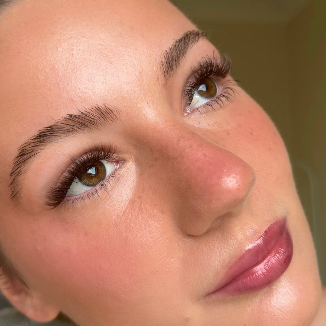 Close-up of a woman's face with a neutral background with false brown eyelashes