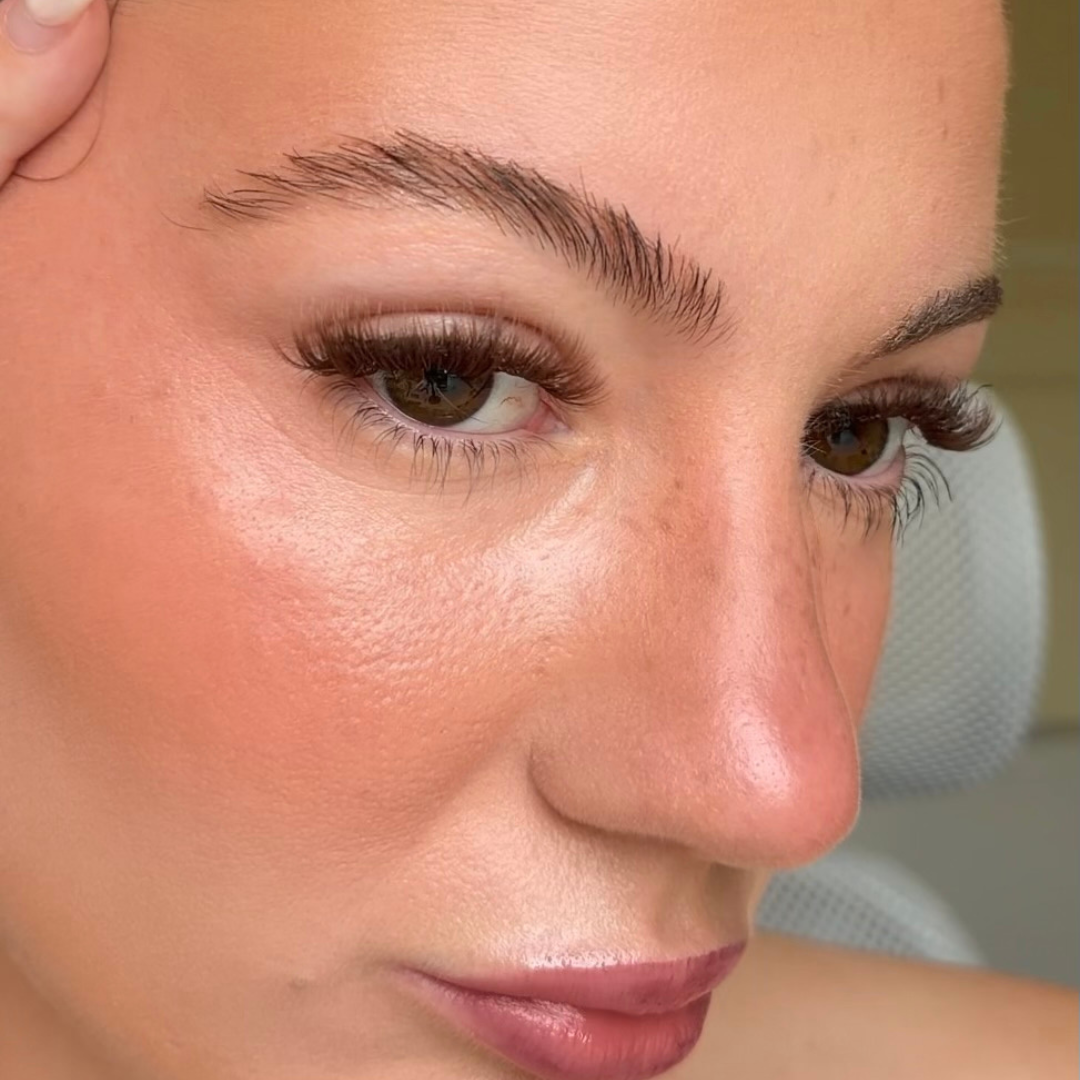 Close-up of a woman's face with makeup, focusing on her brown eyelashes.