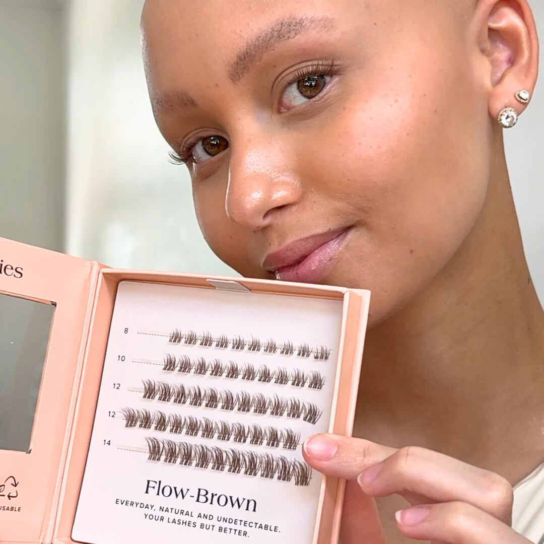 Woman holding a box of false eyelashes with 'Flow Brown' branding.
