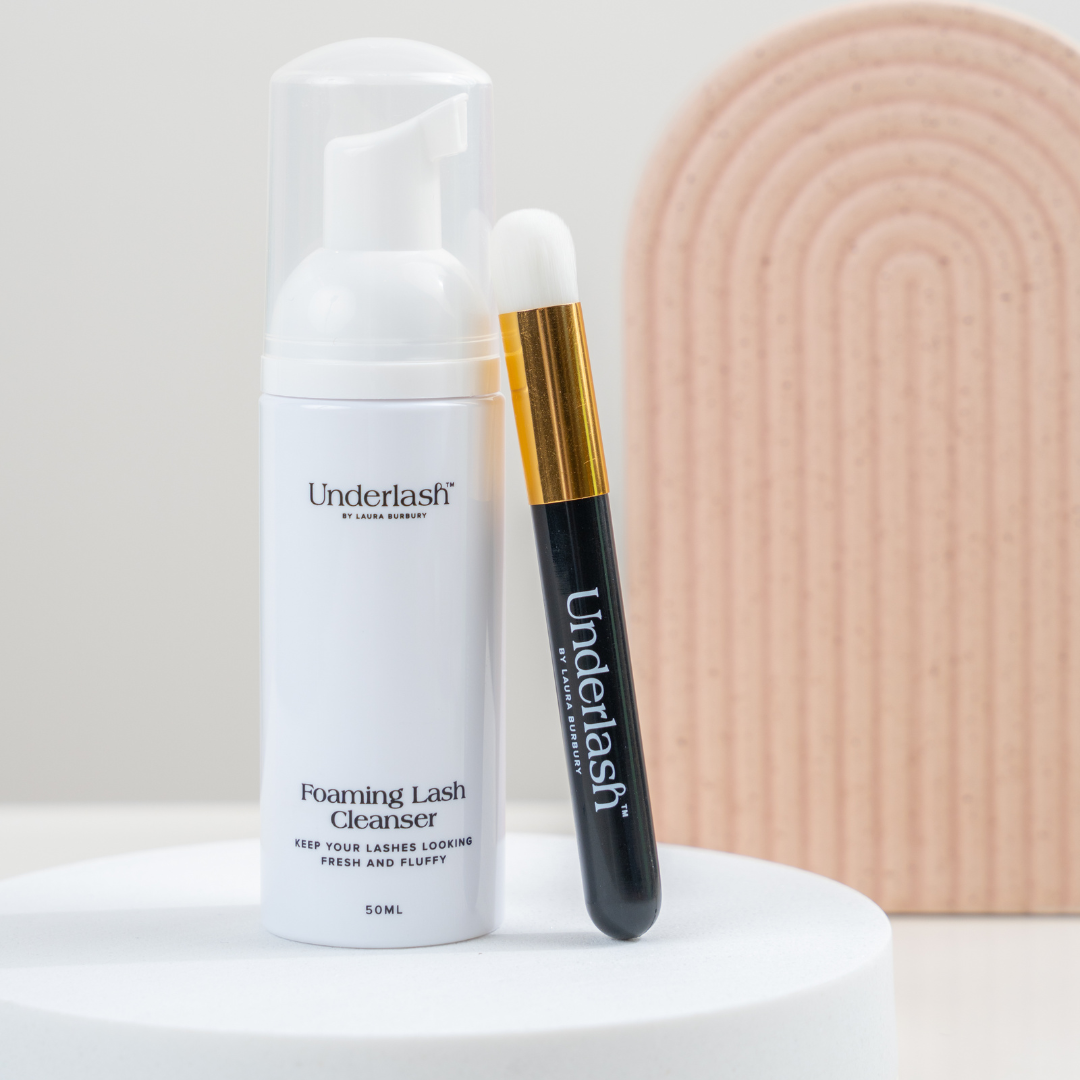 Lash care products including a foaming cleanser and a applicator on a neutral background.