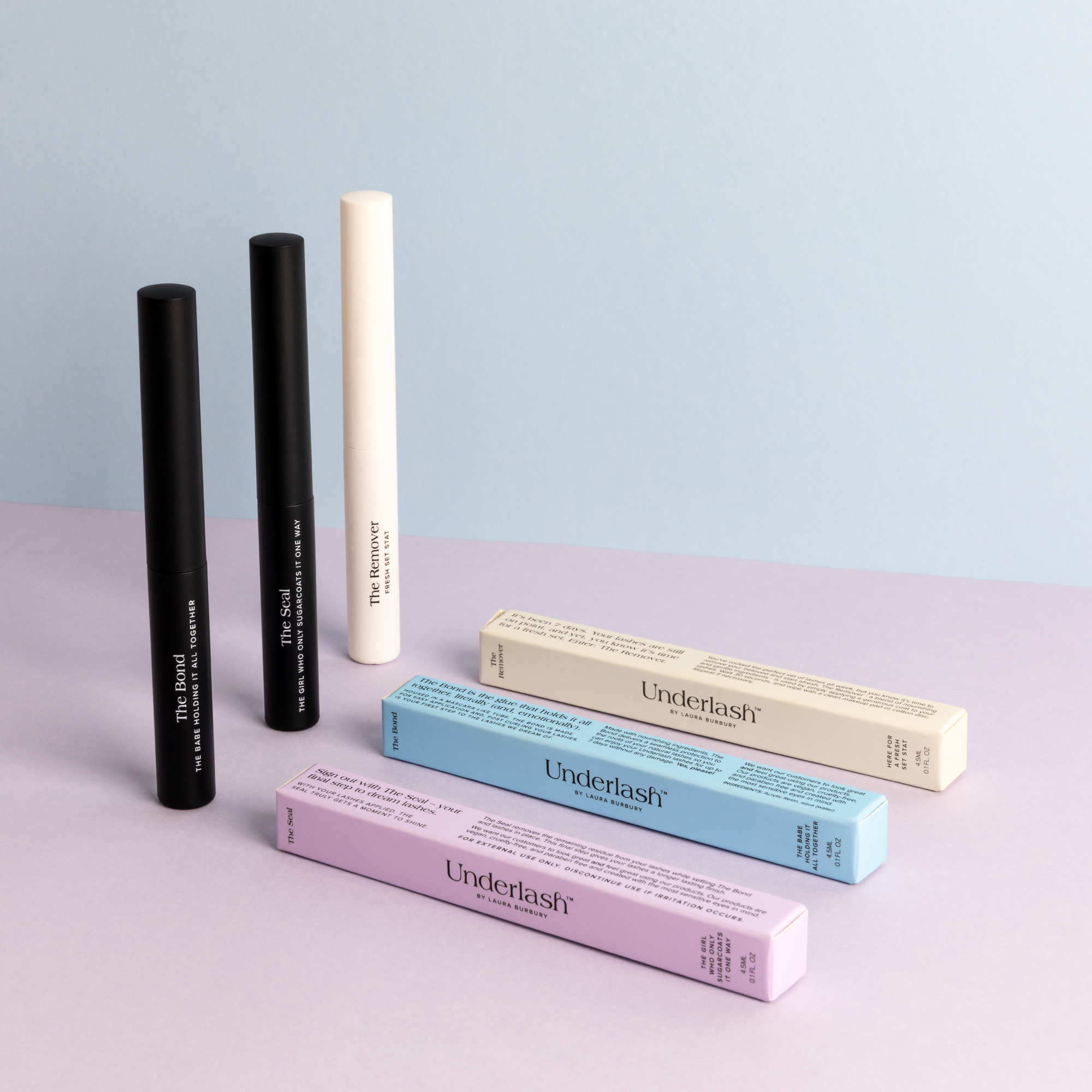 Three cylindrical bottles with packaging, two black and one beige, on a two-tone background.